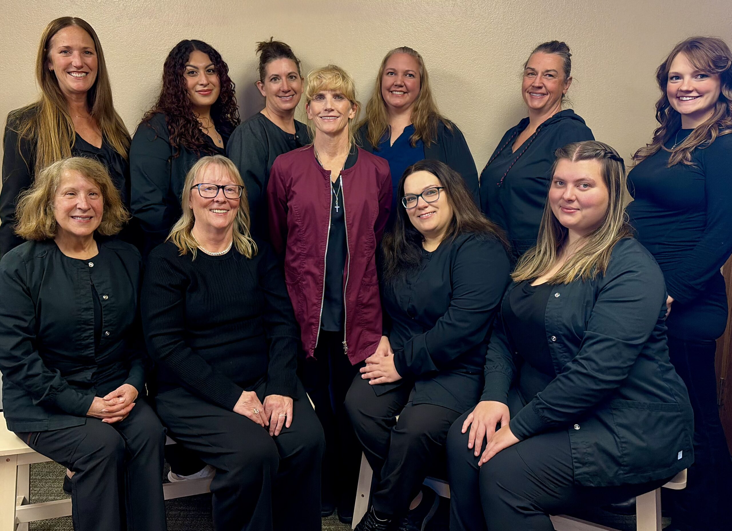 The dental team at Pronghorn Family Dentistry wearing black in front of a brick wall
